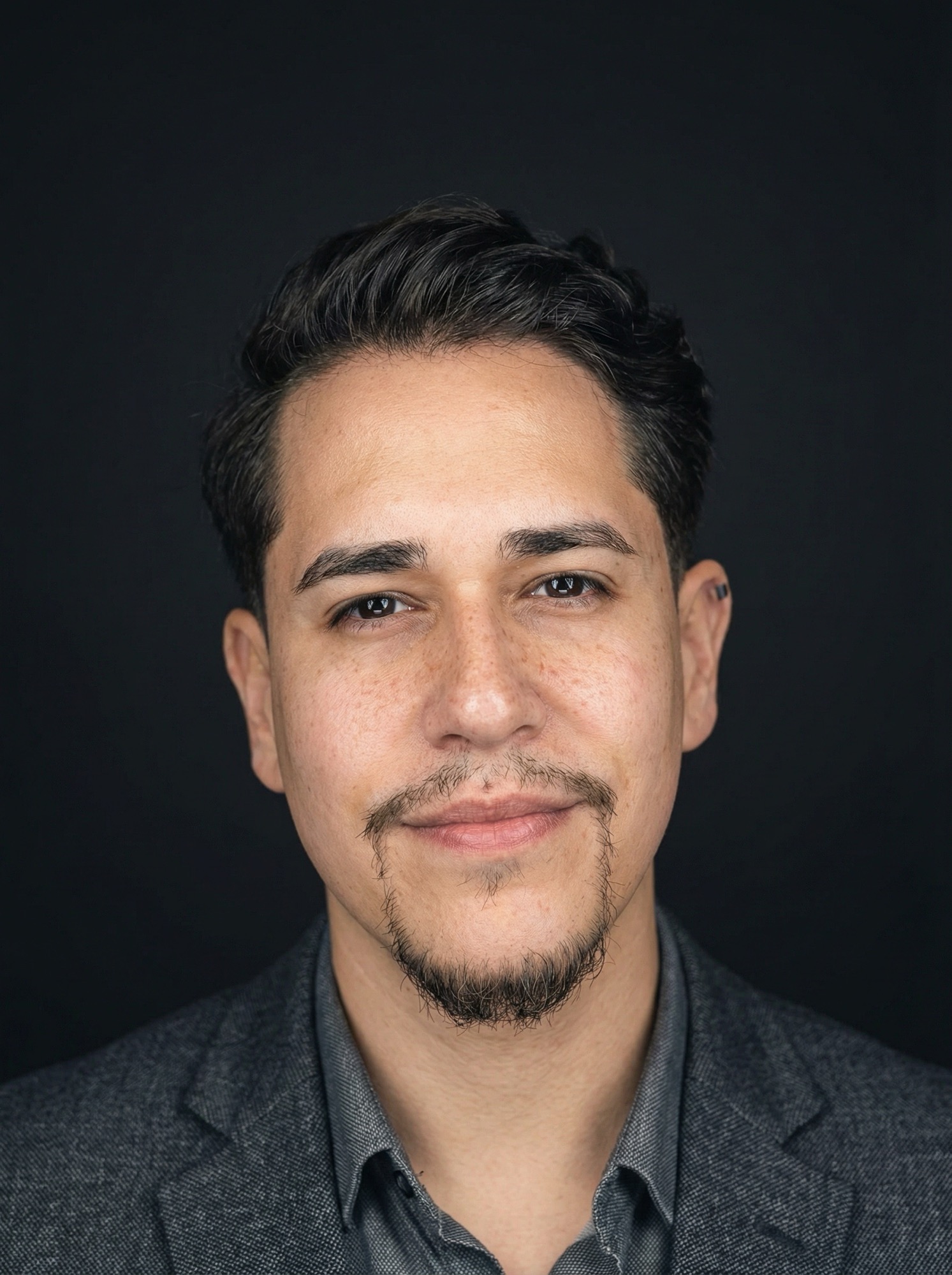 Studio headshot of Christopher Collazo against a dark background